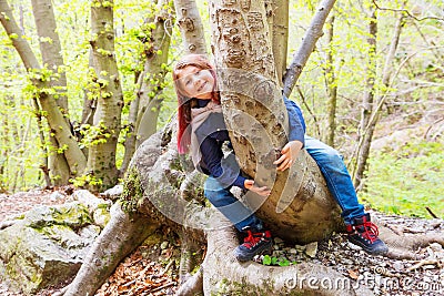 Little girl sitting astride a log in a forest Stock Photo