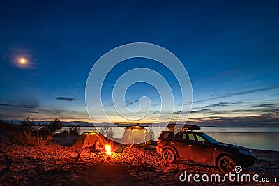 Little girl sitting at bonfire in tourist camping in the evening Stock Photo