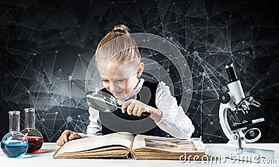 Little girl sitting at desk with magnifier Stock Photo