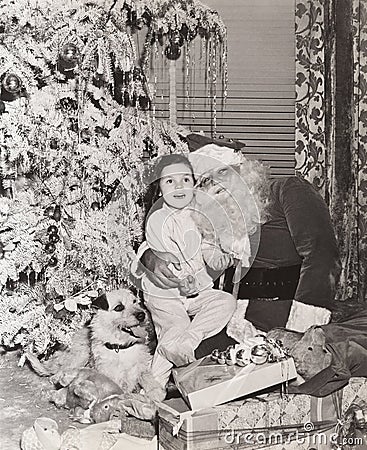 Little girl sitting on Santa's lap under Christmas tree Editorial Stock Photo
