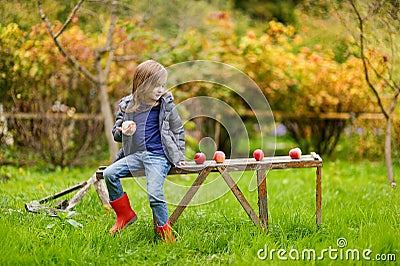 Little girl sitting on a wooden bench on autumn Stock Photo