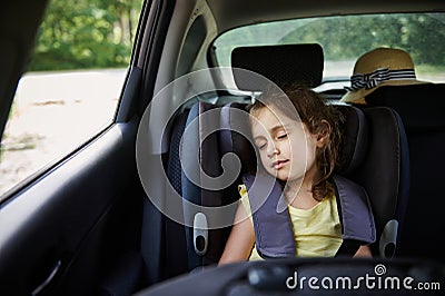 Safe movement of children in the car. Little girl sleeps in a booster seat in the car. Child safety seat Stock Photo