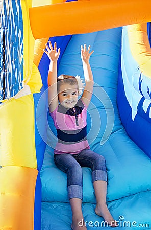 Little Girl sliding down an inflatable Slide Stock Photo