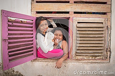 the little girl smiles behind the old window Editorial Stock Photo