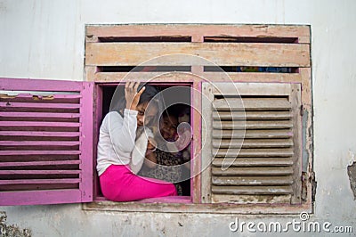 the little girl smiles behind the old window Editorial Stock Photo