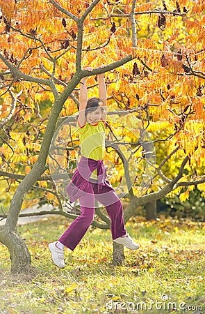 Little girl smiling and hanging on a branch Stock Photo