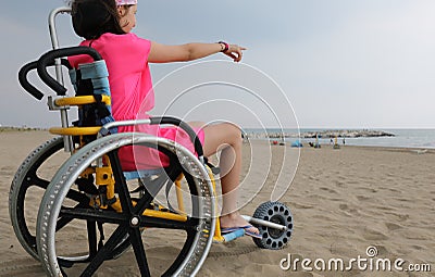 Little girl on the special wheelchair with big wheels in alumini Stock Photo