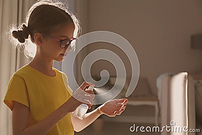 Little girl spraying antiseptic onto hand indoors. Space for text Stock Photo