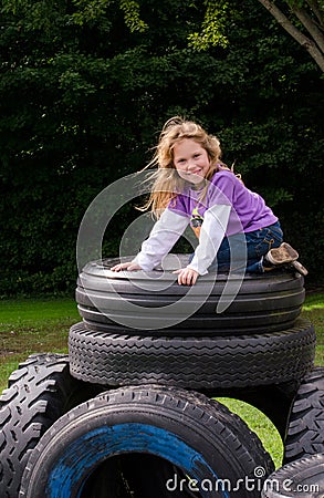 Little girl on stack of recycled tires Stock Photo