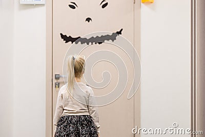 Little girl stand front of door and afraid enter. Stock Photo