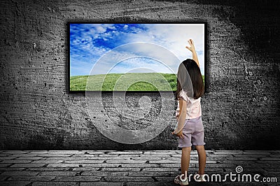 Little girl standing in front of a large monitor Stock Photo