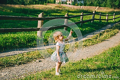 Little girl stands on the country raod and point on somtheing Stock Photo