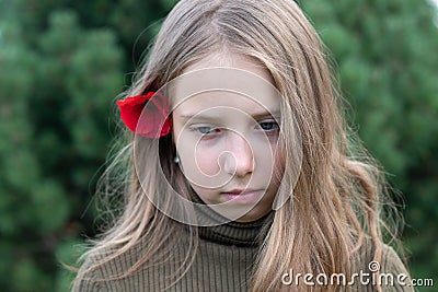 A little girl stands with a red flower behind her ear outside Stock Photo
