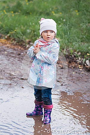 Little girl staying in the puddle and looking at the right Stock Photo