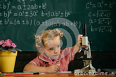 Little girl study in biology classroom at school. Schoolgirl work on biology research with microscope Stock Photo