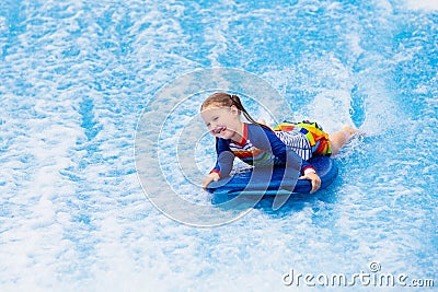 Little girl surfing in beach wave simulator Stock Photo