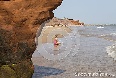 Little girl in swimming suit sitting in shallow water Stock Photo