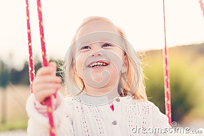 Little girl swinging on a playground. Childhood, Happy, Summer Outdoor Concept Stock Photo