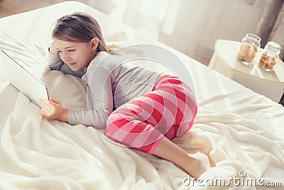 Little girl with tablet computer in bed Stock Photo