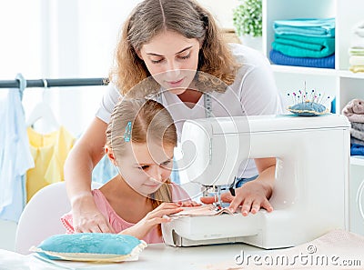 Little girl is taught to sew Stock Photo