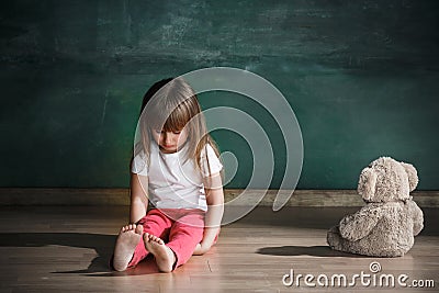 Little girl with teddy bear sitting on floor in empty room. Autism concept Stock Photo