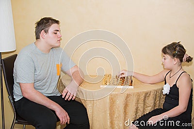 Little girl and teenage boy playing chess Stock Photo