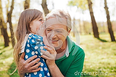 Little girl telling secret to grandpa Stock Photo