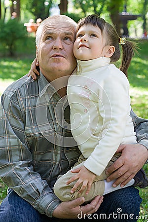 Little girl tenderly embraces grandfather and sits Stock Photo