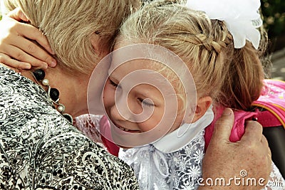 Little girl tenderly embraces grandmother in day back to school Stock Photo