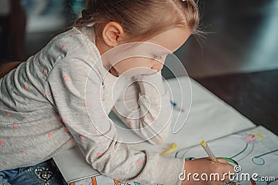 A little girl thoughtfully paints a picture with colored pens. Close-up natural light Stock Photo