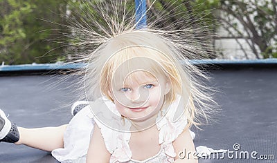 Little Girl Toddler Plays on a Trampoline and has Static Electricity in Her hair Stock Photo