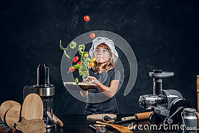 Little girl is tossing vegetables on the pan Stock Photo