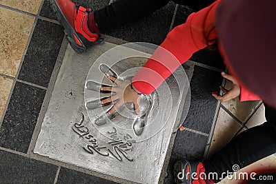 Little girl touching a hand print of famous actor in front of the Cannes Casino, where the Cannes film festival takes place Editorial Stock Photo