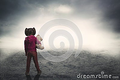 Little girl with toy bear in the darkness Stock Photo