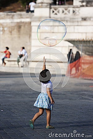 Little girl tries to reach soap bubble flying Editorial Stock Photo