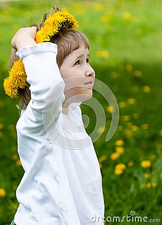 Little girl trying on yellow chaplet made of dandelions Stock Photo