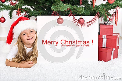 Little girl under the christmas tree with banner Stock Photo