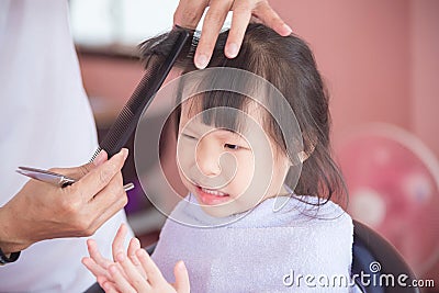 Little girl unhappy with first haircut by hairdresser Stock Photo