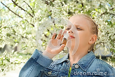 Little girl using nasal drops near blooming tree. Allergy concept Stock Photo