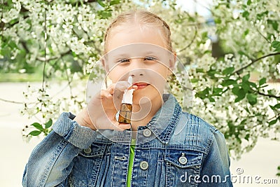 Little girl using nasal drops near blooming tree. Allergy concept Stock Photo