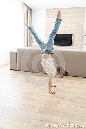 Girl standing upside down on her arms at home Stock Photo