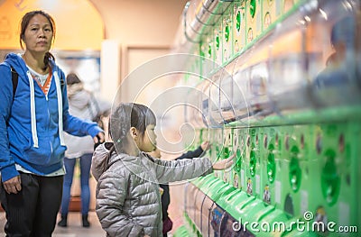 Little girl wanting Toys from Japanese Toys vending machine Editorial Stock Photo