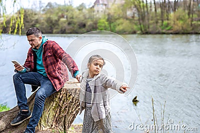 The little girl wants to go out with her dad, but he is busy with the phone Stock Photo