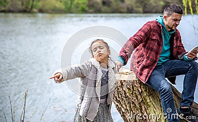 The little girl wants to go out with her dad, but he is busy with the phone Stock Photo