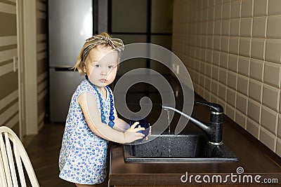 Little girl washing dishes in the kitchen at home Stock Photo