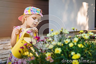 Little girl watering flowers with yellow watering can Stock Photo