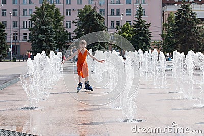 Little girl in wet dress roller skates in fountain in summ Stock Photo