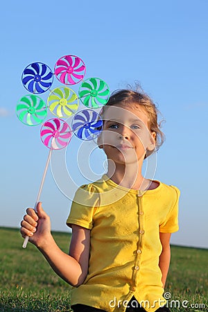 Little girl with whirligig sits at grass Stock Photo