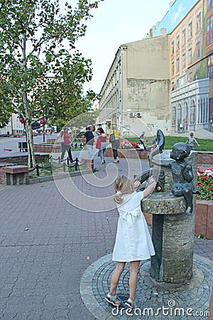Little girl in white dress is naught with water in city statue fountain Editorial Stock Photo