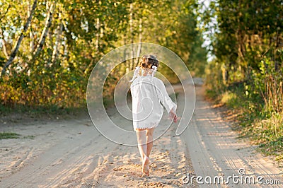 A little girl in a white traditional Ñhemise running in a scenic early autumn landscape Stock Photo